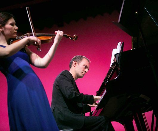 Une violoniste et un pianiste sur scène en train de jouer