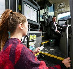 Jeune fille qui monte dans un car, le chauffeur regarde l'obejctif